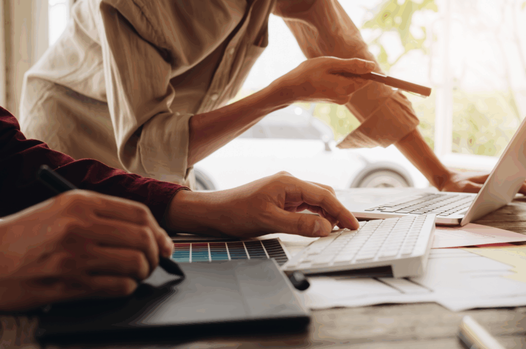 2 people, laptop, pen, and papers